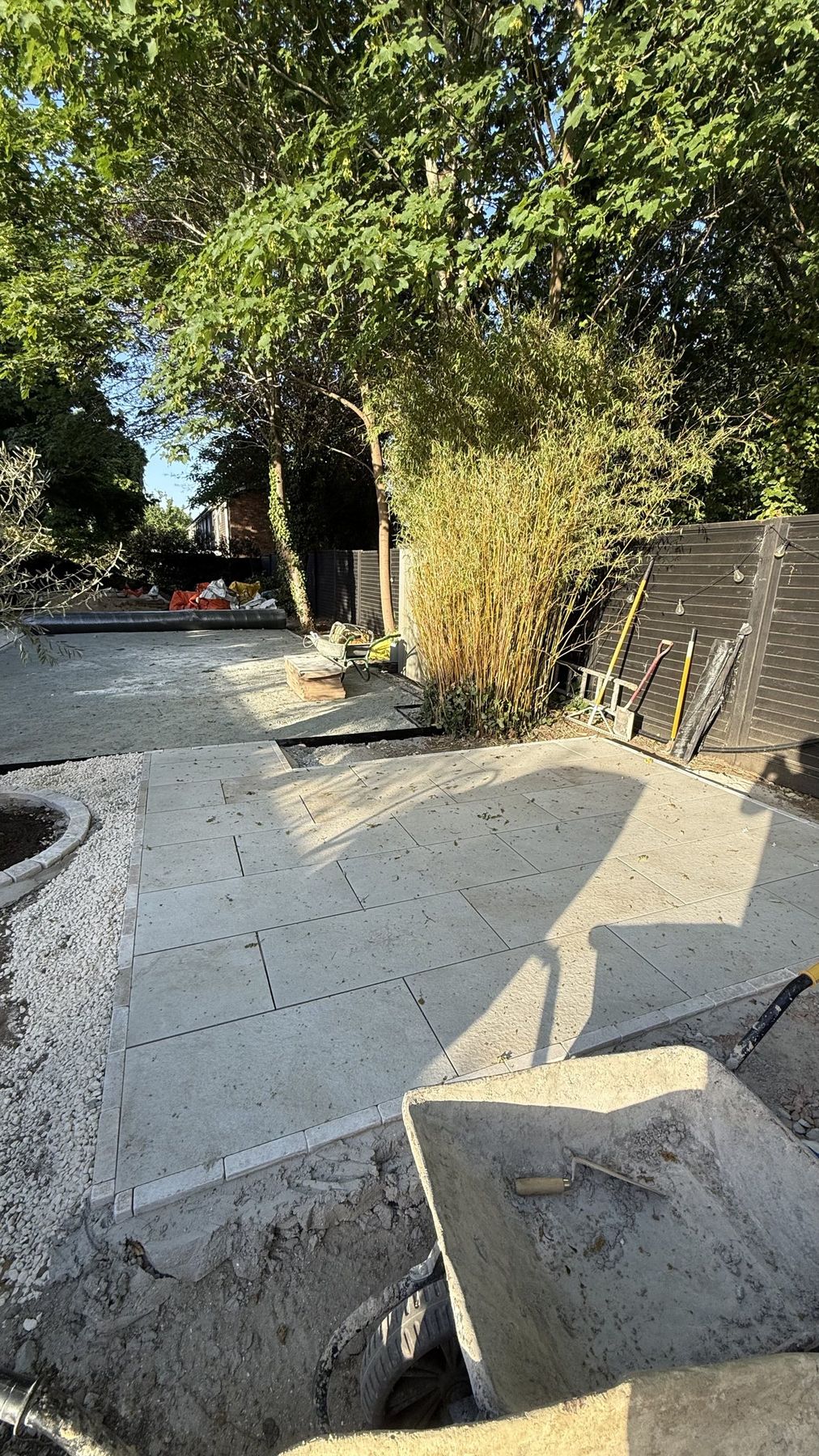 Patio slabs being laid alongside a new rendered planter